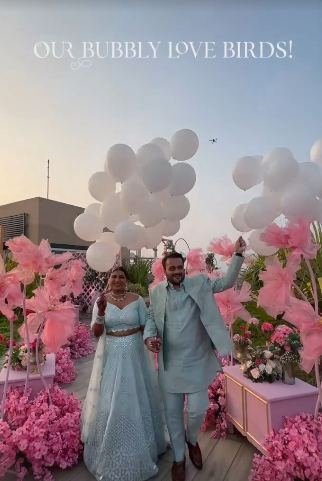 Couple walking in past pink florals and white balloons